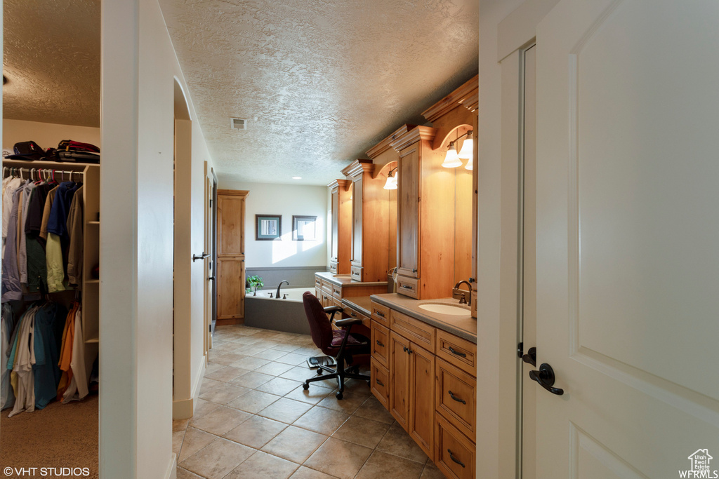 Bathroom featuring tile patterned flooring, a tub, vanity, and a textured ceiling