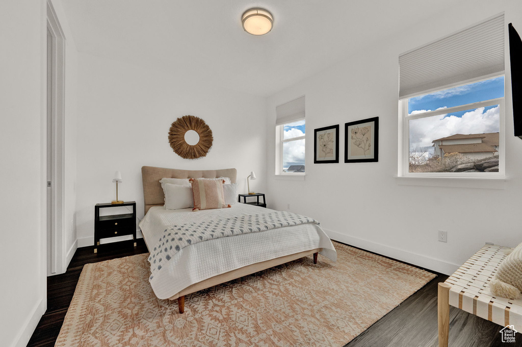 Bedroom featuring multiple windows and dark hardwood / wood-style flooring