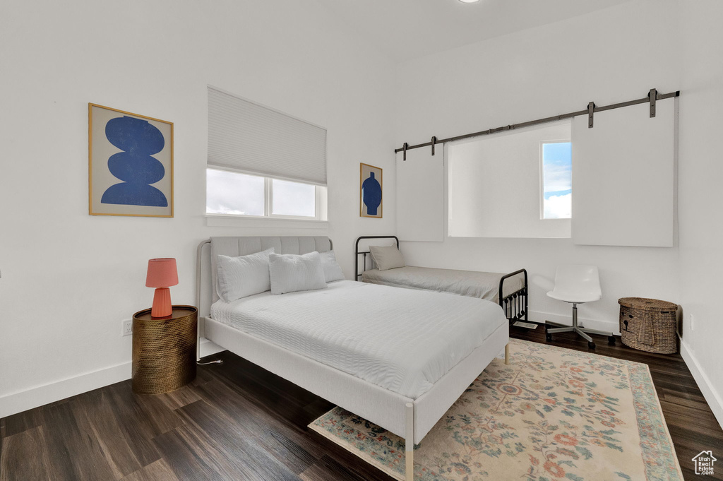 Bedroom featuring dark hardwood / wood-style floors and a barn door