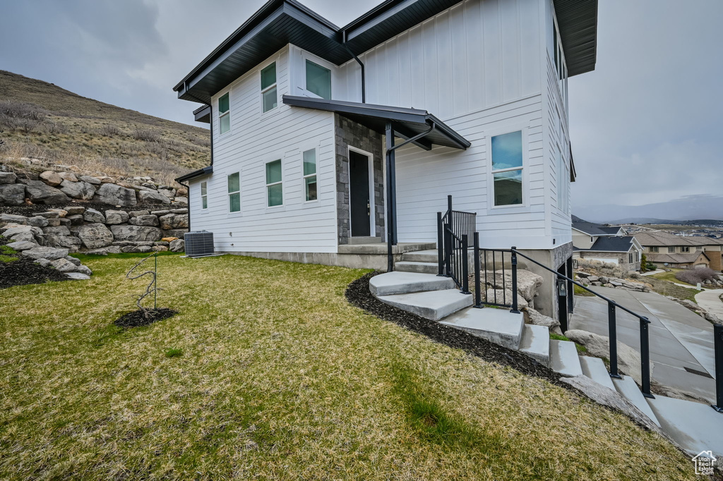 Back of house featuring central air condition unit and a lawn