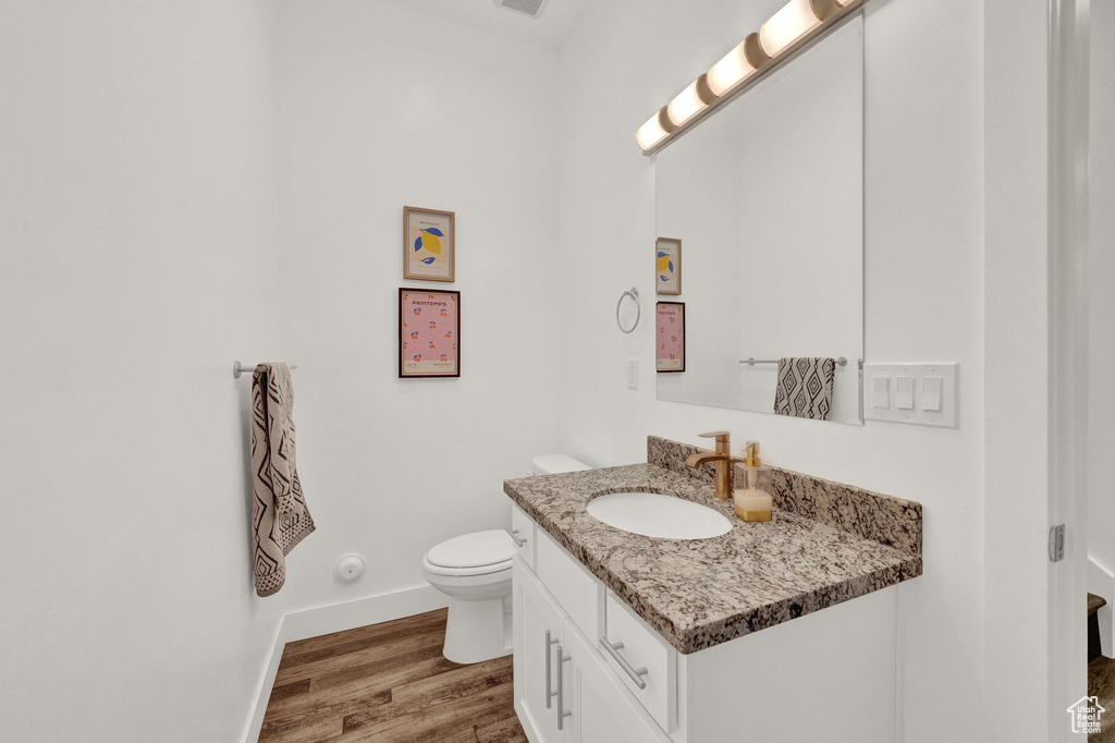 Bathroom with hardwood / wood-style flooring, toilet, and vanity