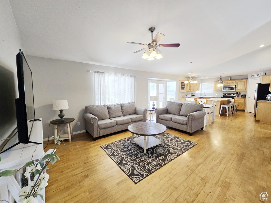 Living room with sink, ceiling fan with notable chandelier, and light wood-type flooring