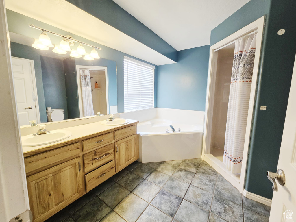 Full bathroom featuring independent shower and bath, toilet, tile patterned floors, and dual bowl vanity