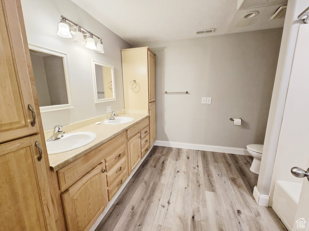 Bathroom featuring hardwood / wood-style flooring, toilet, and dual bowl vanity