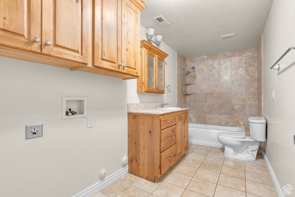 Full bathroom featuring vanity, tile patterned floors, tiled shower / bath, toilet, and a textured ceiling