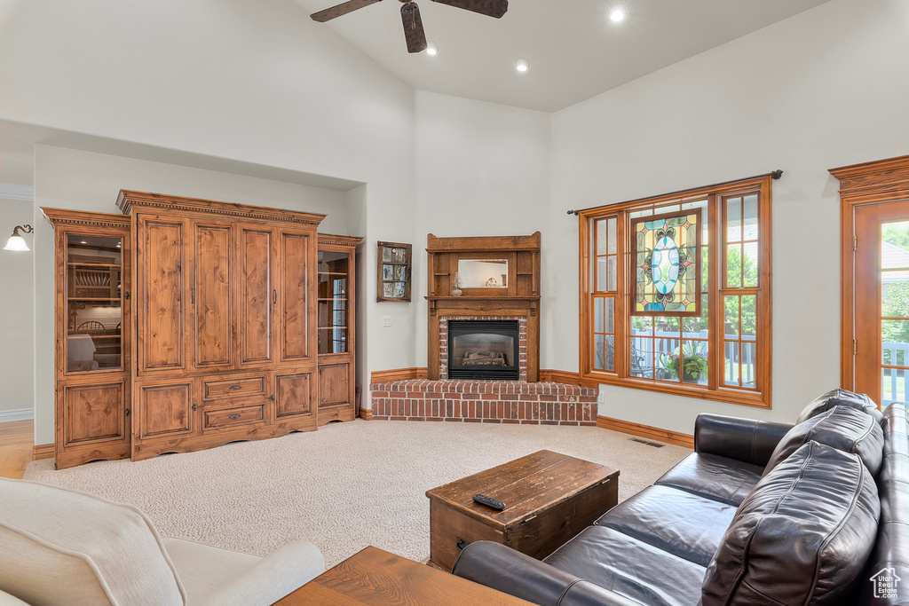 Living room with a high ceiling, a fireplace, carpet, and ceiling fan