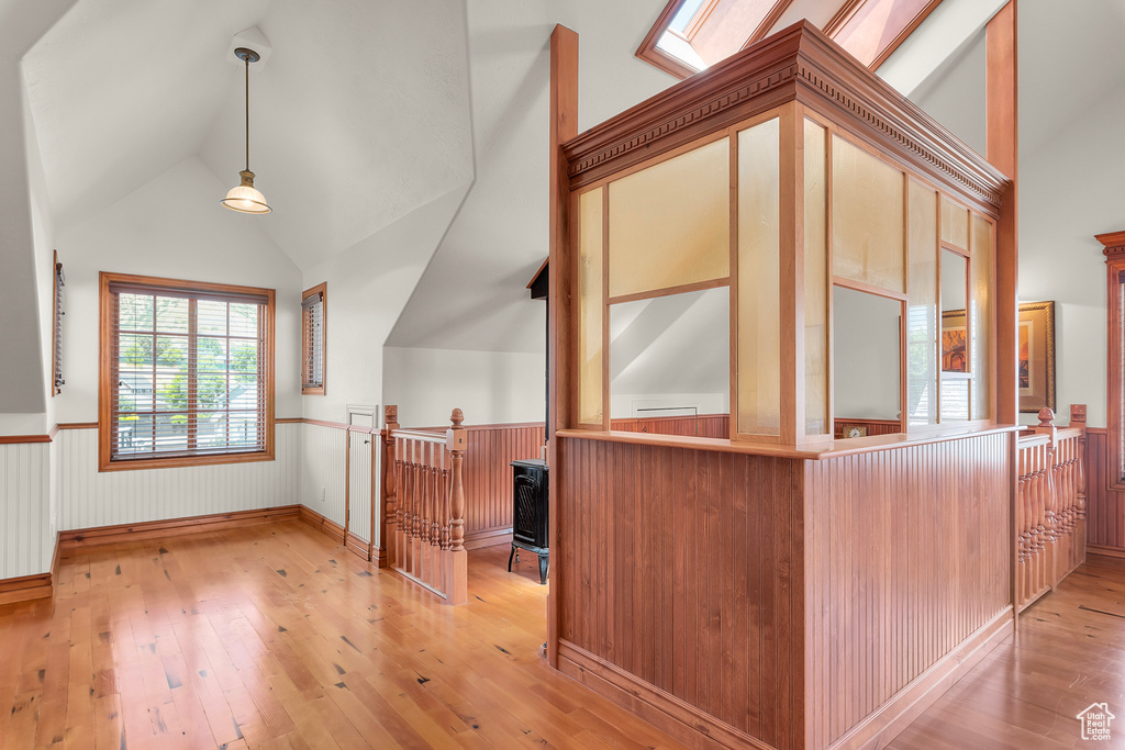 Interior space featuring decorative light fixtures, high vaulted ceiling, light wood-type flooring, a skylight, and kitchen peninsula