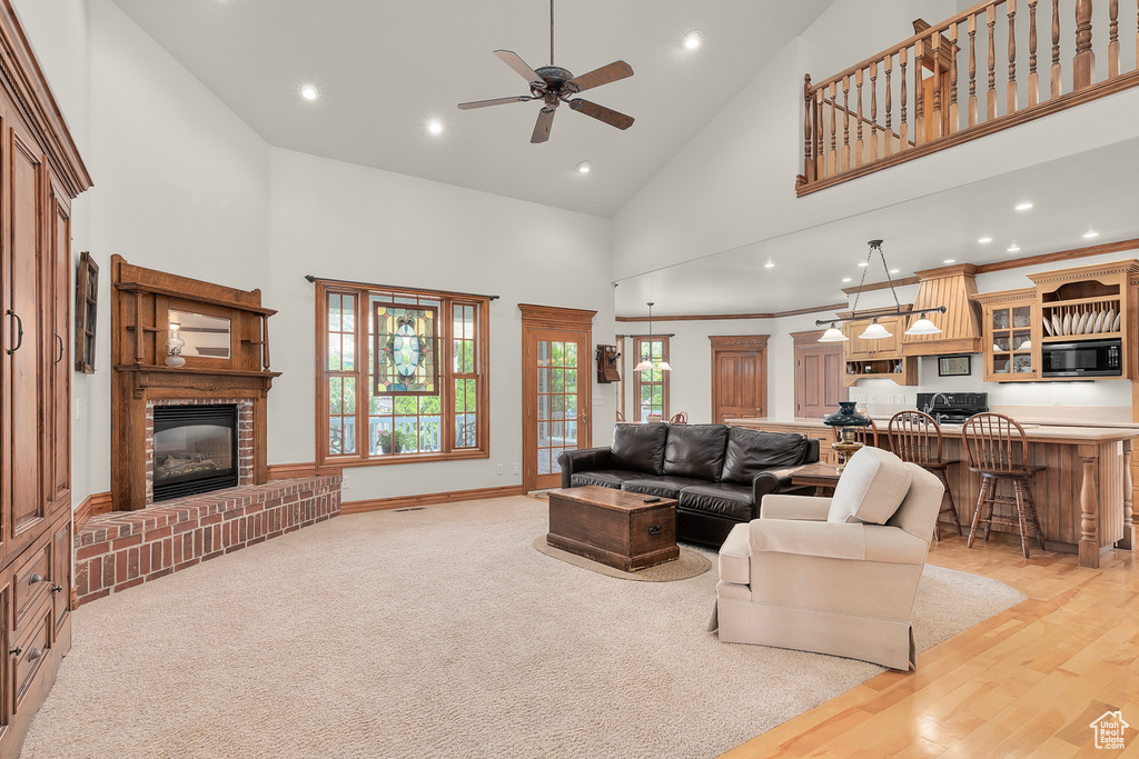 Living room with light carpet, a brick fireplace, high vaulted ceiling, and plenty of natural light