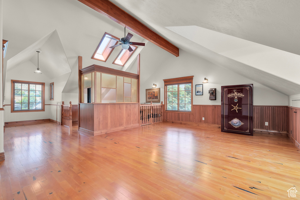 Additional living space featuring vaulted ceiling with skylight, wood-type flooring, a wealth of natural light, and ceiling fan