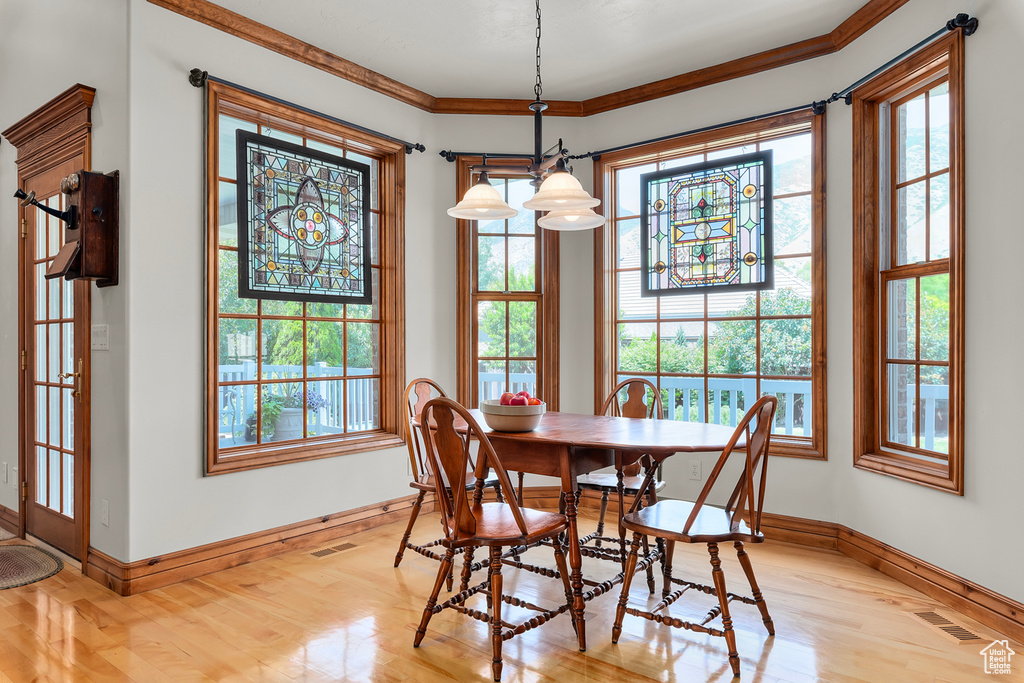 Dining space featuring plenty of natural light, ornamental molding, and light hardwood / wood-style floors