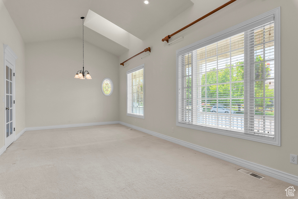 Empty room featuring carpet floors, vaulted ceiling, and a chandelier