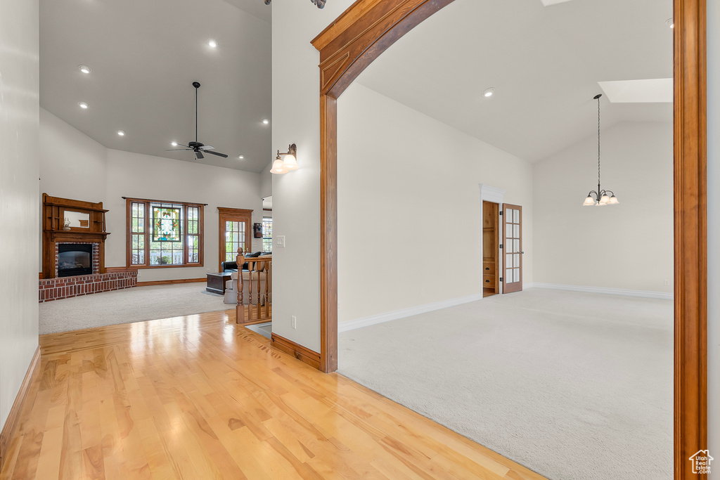 Hallway with light carpet, an inviting chandelier, and high vaulted ceiling