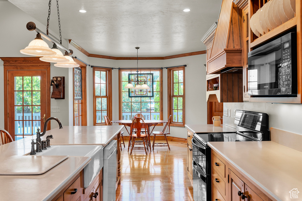 Kitchen with electric range, a chandelier, black microwave, pendant lighting, and ornamental molding