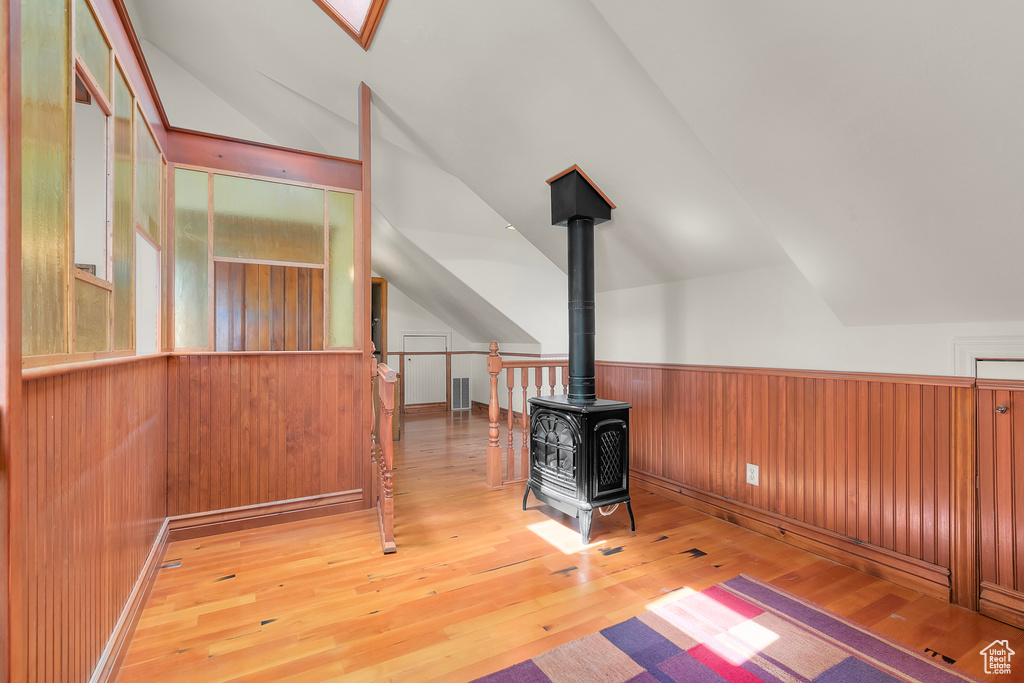 Interior space with light wood-type flooring, lofted ceiling, and a wood stove