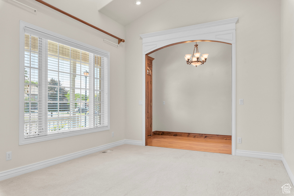 Spare room with a notable chandelier and carpet flooring