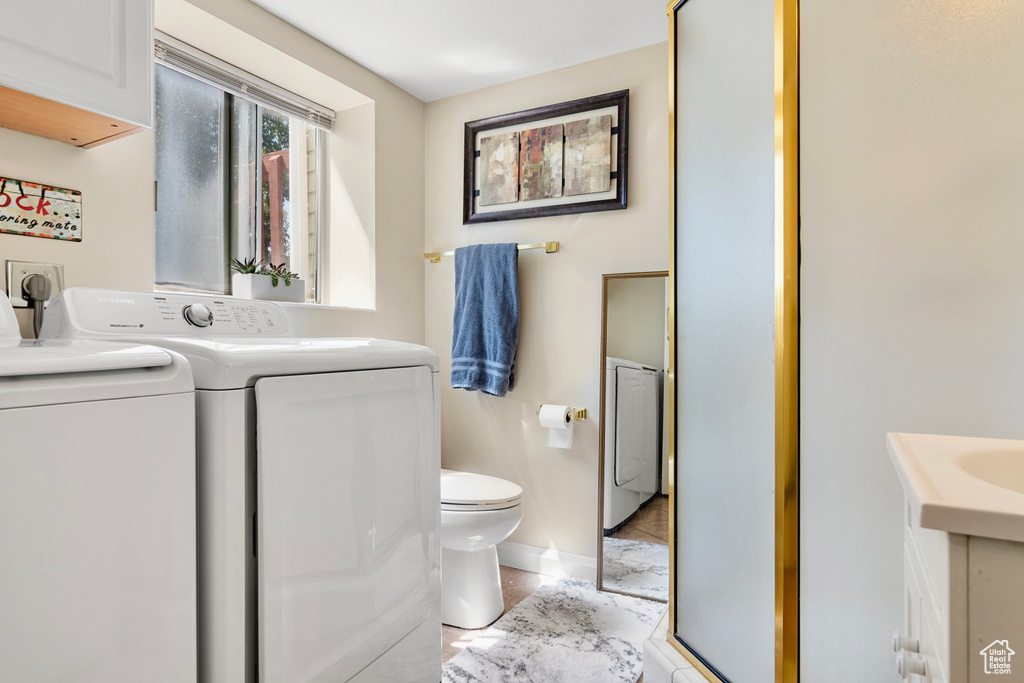 Bathroom featuring tile patterned flooring, washing machine and clothes dryer, toilet, and vanity