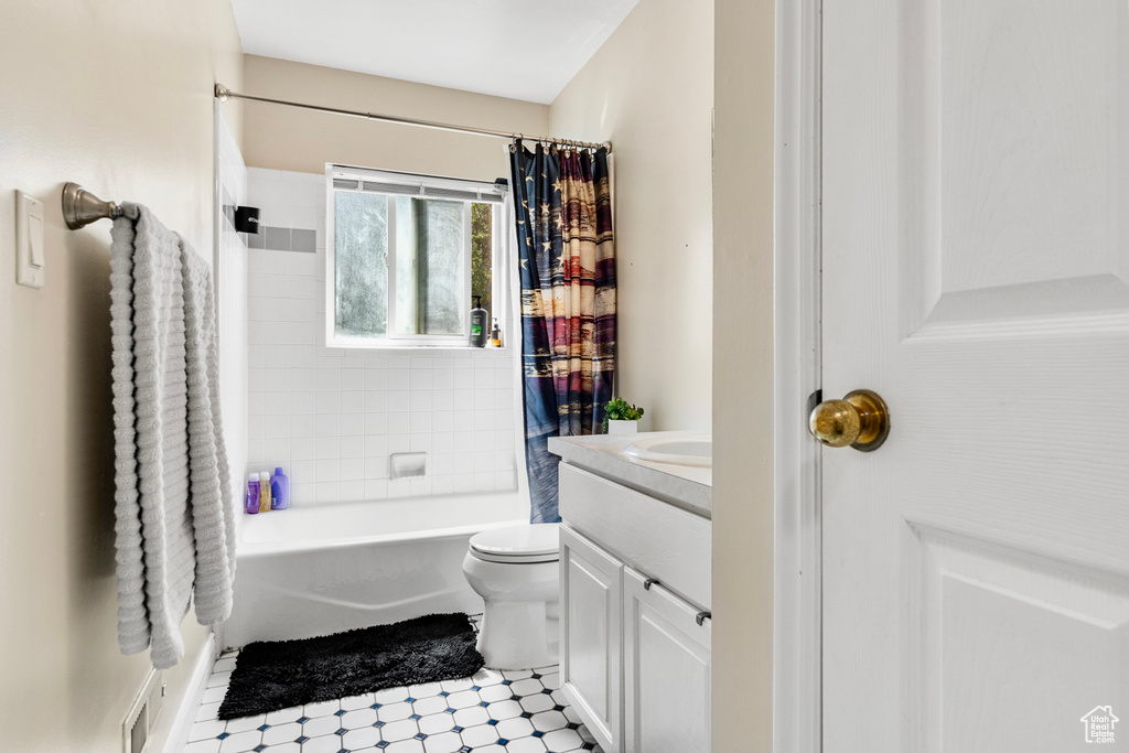 Full bathroom with vanity, shower / tub combo, tile patterned flooring, and toilet