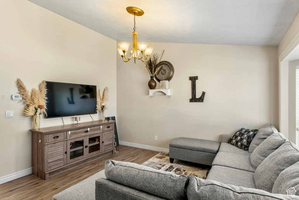 Living room featuring light hardwood / wood-style floors, vaulted ceiling, and a chandelier