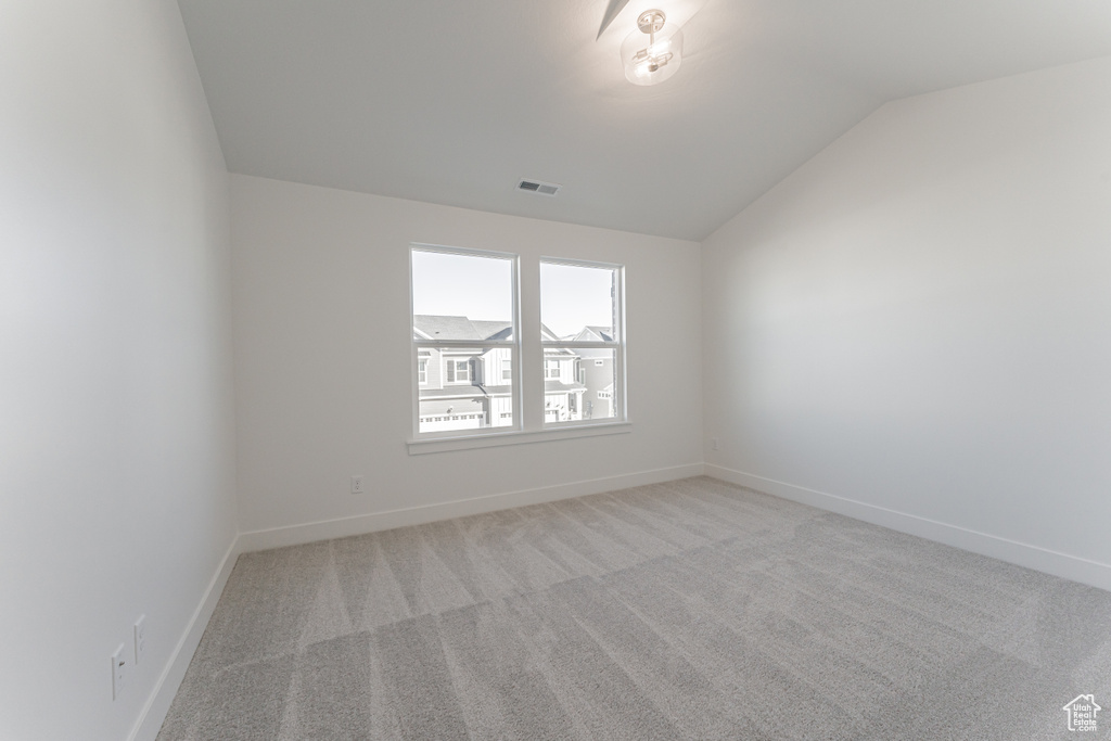 Carpeted empty room with vaulted ceiling