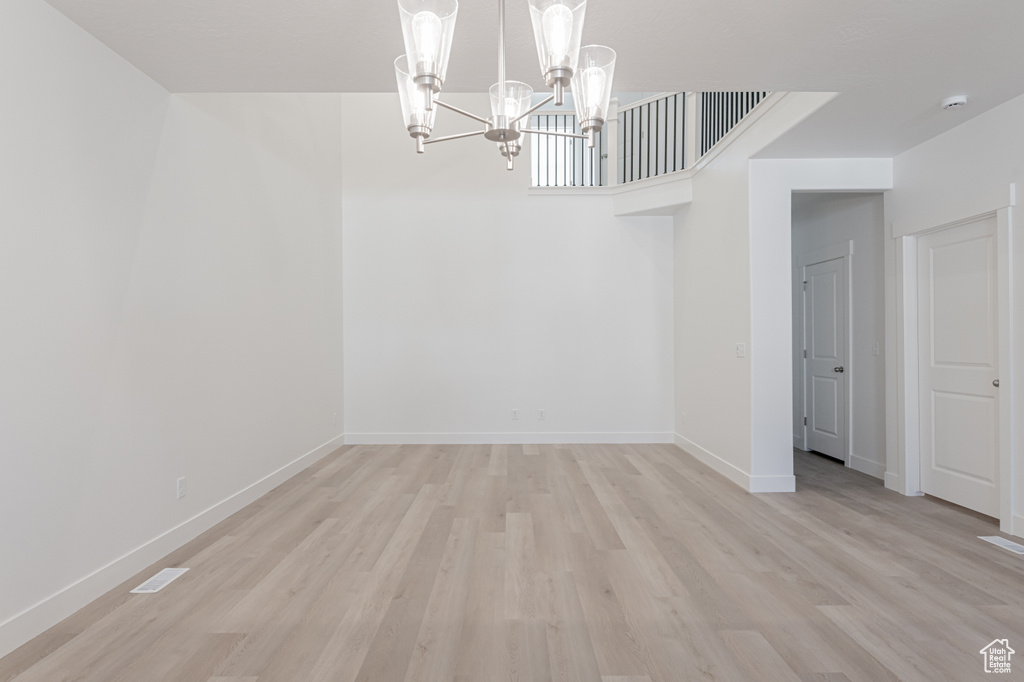 Unfurnished dining area featuring a chandelier and light wood-type flooring