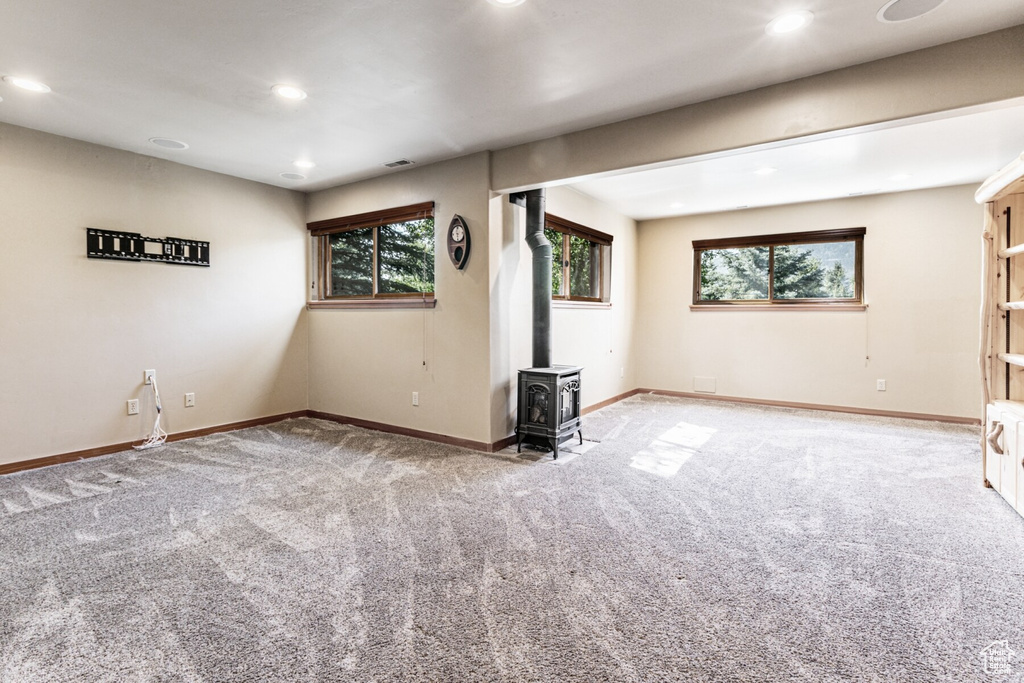 Interior space with carpet flooring, a wealth of natural light, and a wood stove