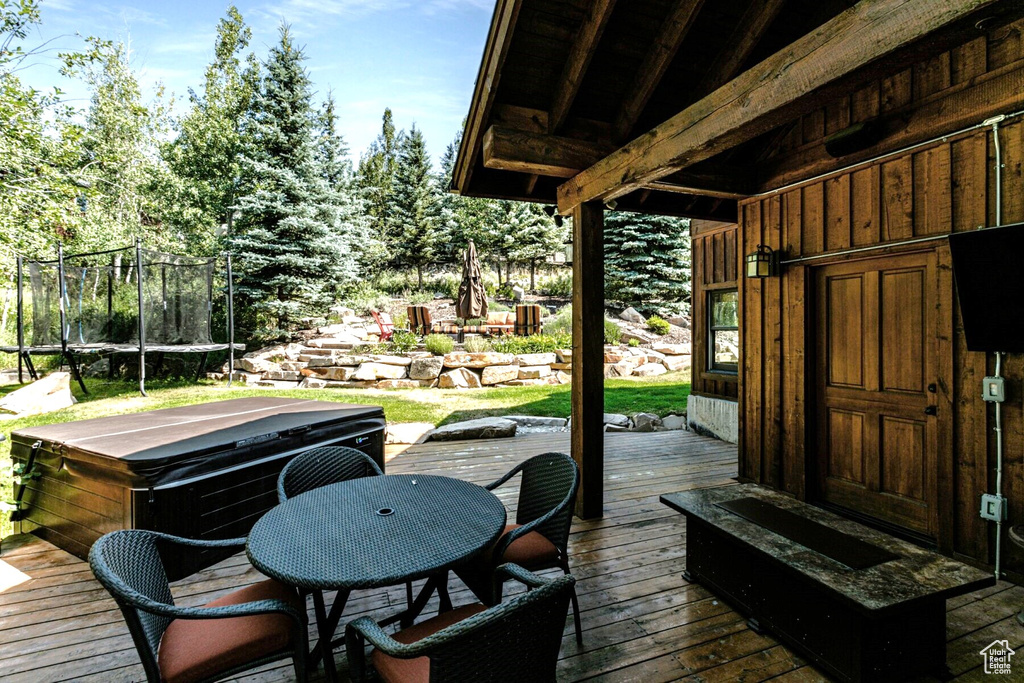 Wooden terrace with a trampoline and a hot tub