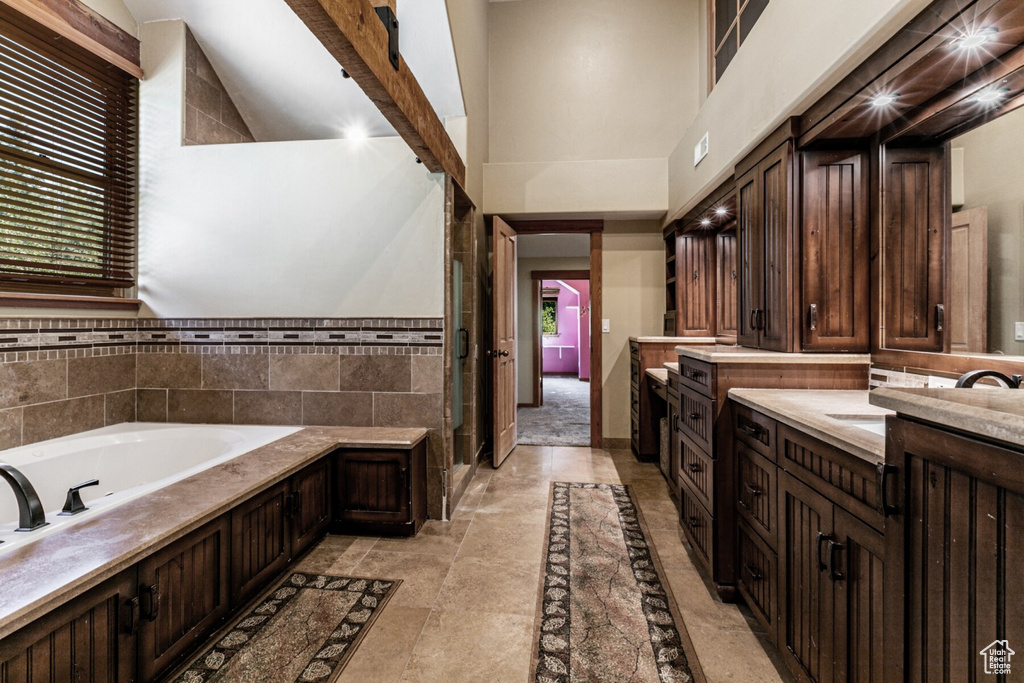 Bathroom featuring vanity, a high ceiling, beamed ceiling, a washtub, and tile patterned flooring