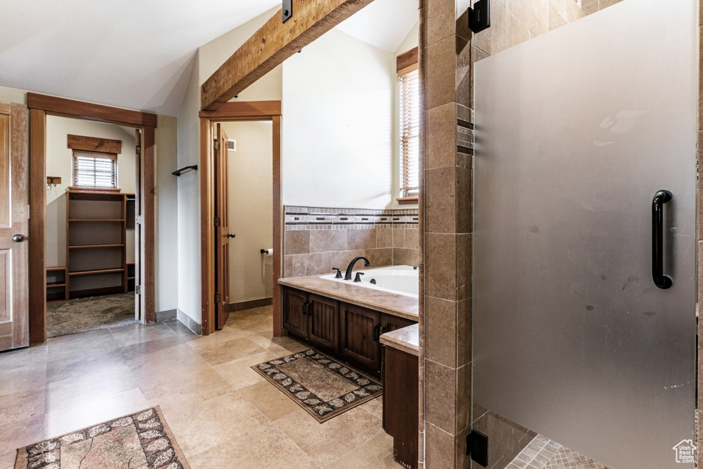 Bathroom with vaulted ceiling, independent shower and bath, and tile patterned floors