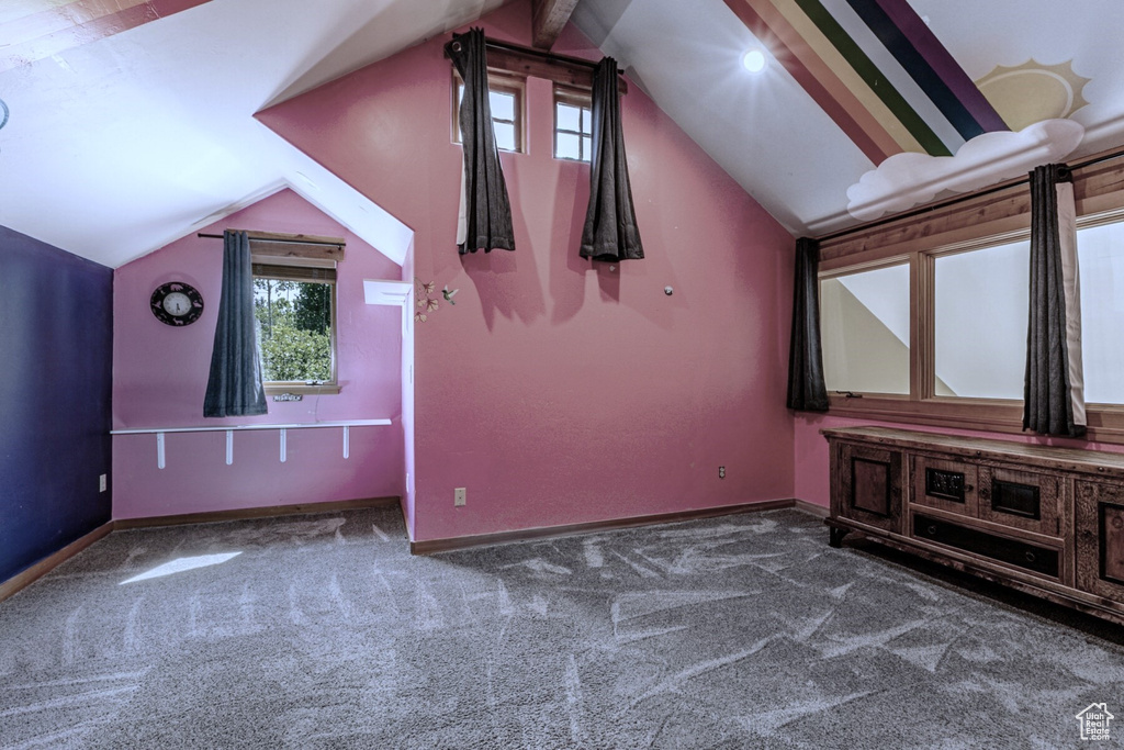 Additional living space with dark colored carpet and vaulted ceiling