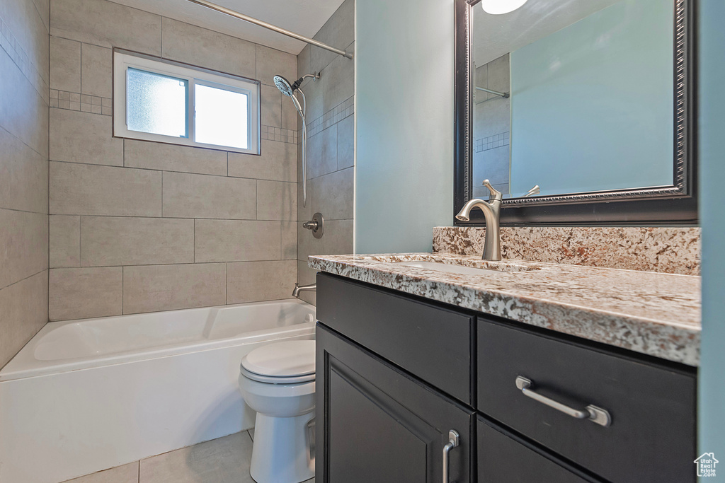 Full bathroom with vanity, tiled shower / bath combo, and toilet