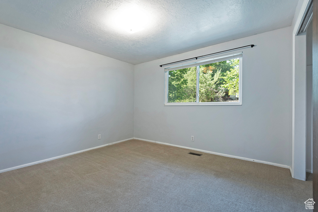 Carpeted spare room featuring a textured ceiling