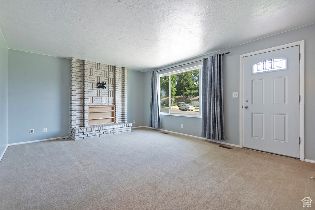 Carpeted entryway featuring brick wall and a textured ceiling