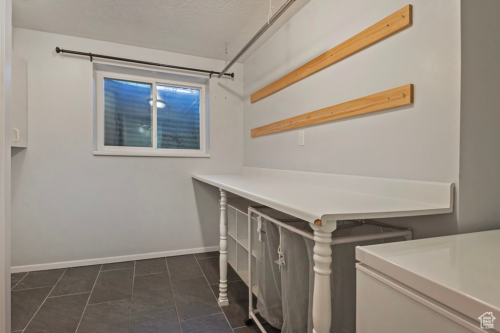 Clothes washing area featuring a textured ceiling and dark tile patterned flooring