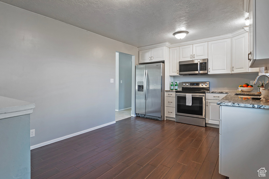 Kitchen featuring white cabinetry, stainless steel appliances, sink, dark hardwood / wood-style floors, and a textured ceiling