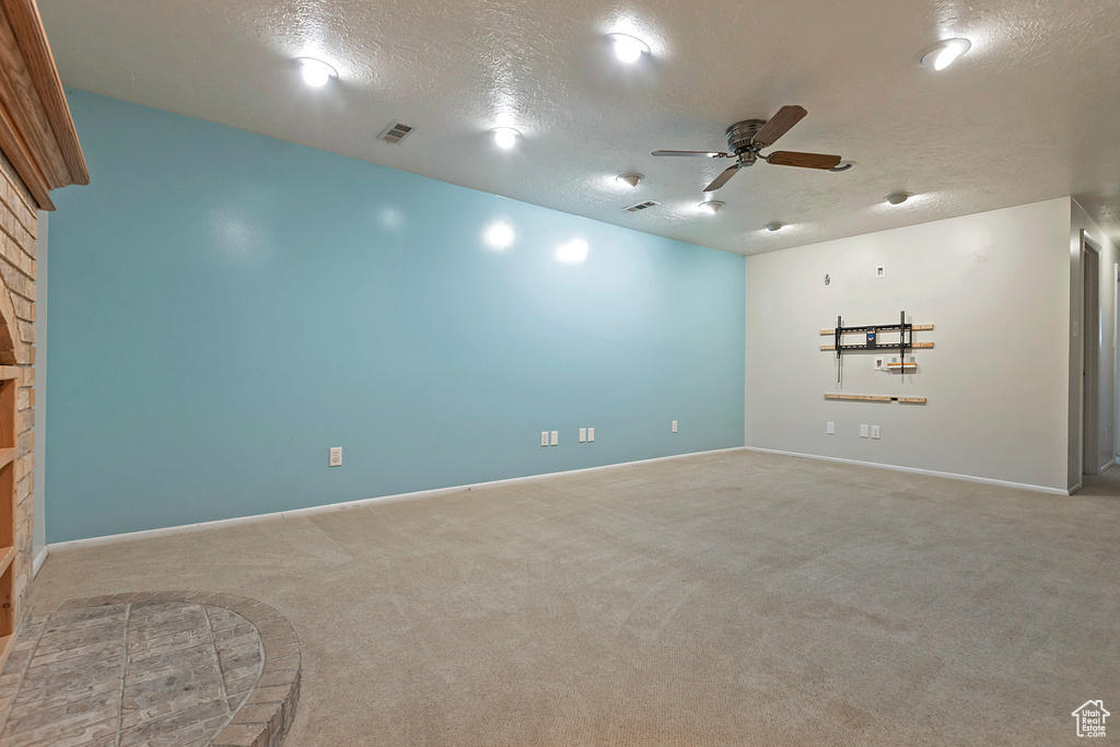 Empty room with carpet flooring, a textured ceiling, and ceiling fan