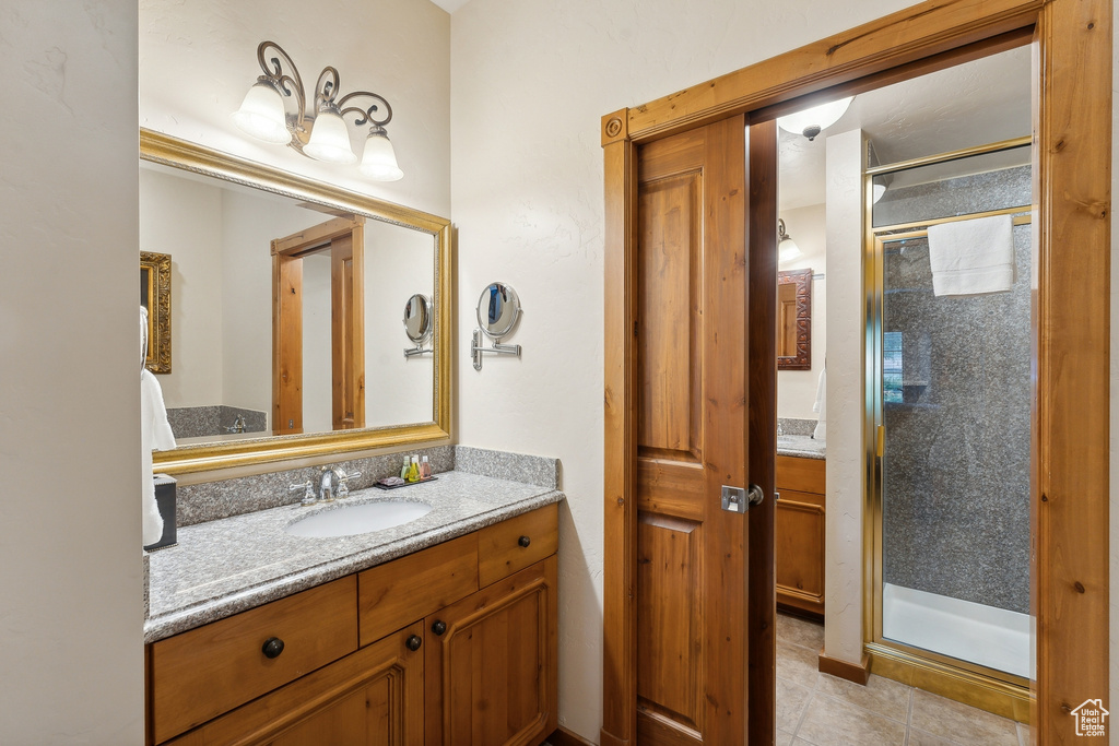 Bathroom featuring tile patterned flooring, a shower with door, and vanity