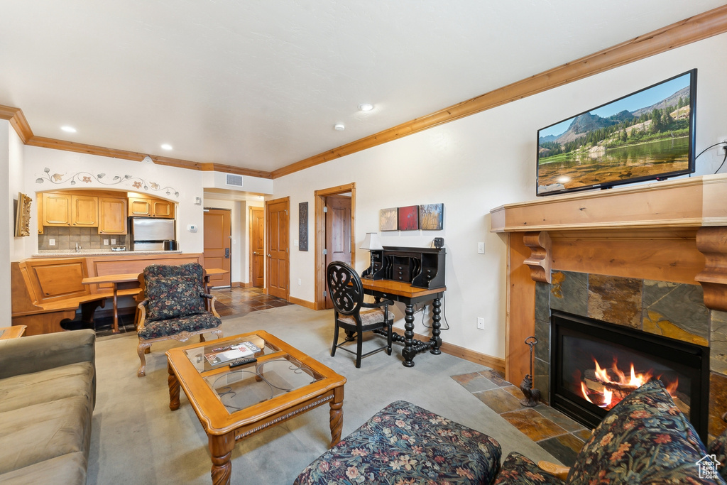 Living room featuring light carpet, a fireplace, and crown molding