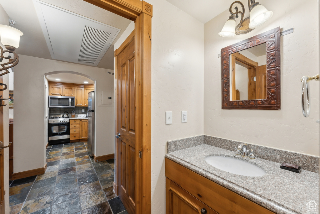 Bathroom featuring vanity, tile patterned flooring, and tasteful backsplash