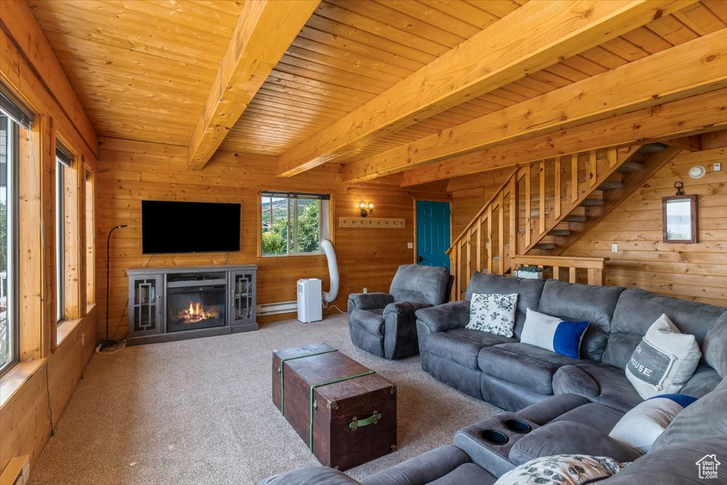 Unfurnished living room featuring wooden walls, carpet flooring, beam ceiling, baseboard heating, and wood ceiling