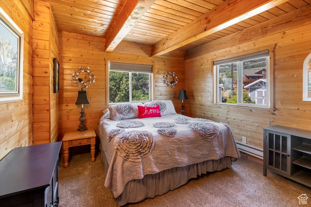Bedroom with beamed ceiling, a baseboard heating unit, multiple windows, and carpet flooring