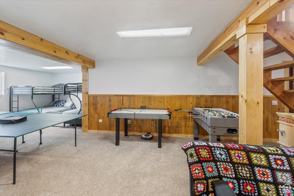 Recreation room with beamed ceiling and carpet flooring