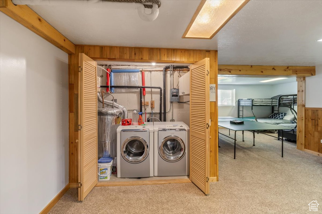 Laundry room featuring wood walls, carpet floors, and washer and clothes dryer
