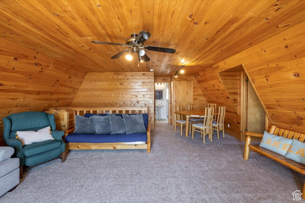 Carpeted bedroom featuring vaulted ceiling, wooden walls, and wooden ceiling