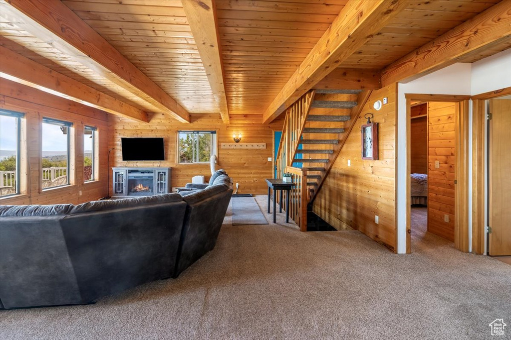 Living room with a healthy amount of sunlight, wooden ceiling, carpet flooring, and beam ceiling