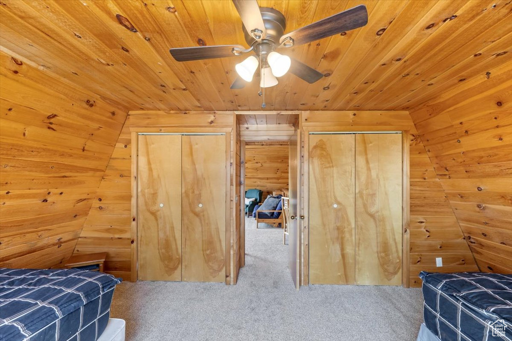Carpeted bedroom with ceiling fan, lofted ceiling, wooden walls, and wooden ceiling