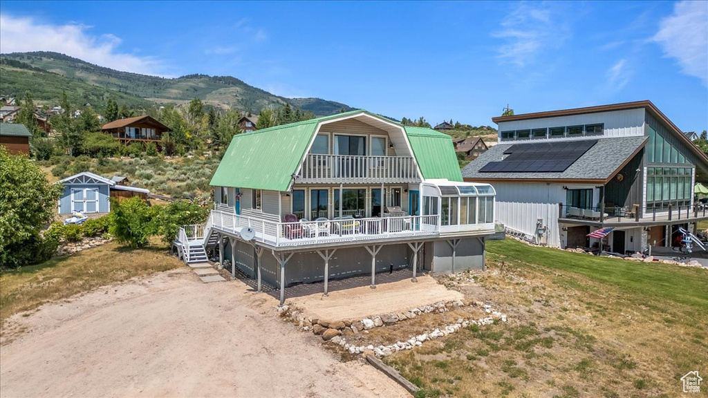 Rear view of house with a mountain view, a balcony, a shed, a yard, and solar panels