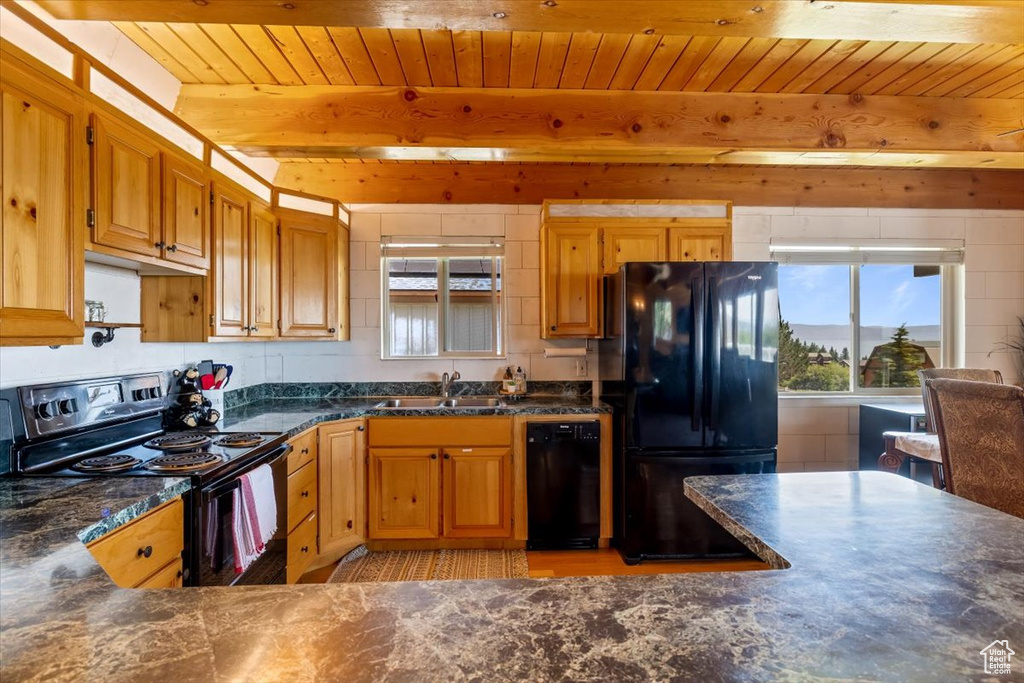 Kitchen with beamed ceiling, sink, black appliances, and a healthy amount of sunlight