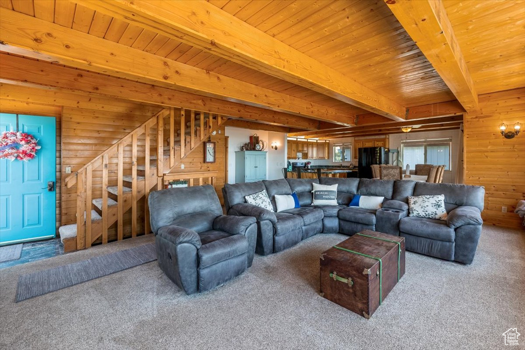 Carpeted living room featuring wood ceiling, wood walls, and beam ceiling
