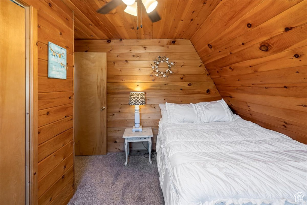 Unfurnished bedroom with wood walls, carpet floors, ceiling fan, wooden ceiling, and vaulted ceiling