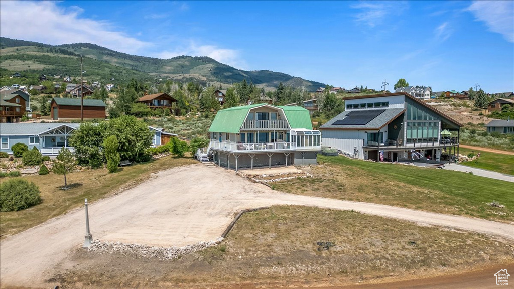 View of front of property with a mountain view, a front yard, and solar panels
